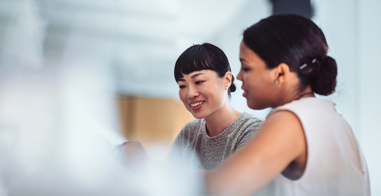 two women looking at computer and smiling